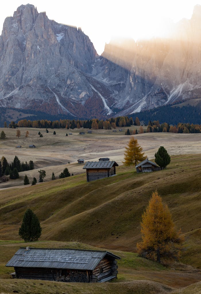 Beautiful landscape of wooden cabins in the Dolomites with sunset lighting and autumn colors.