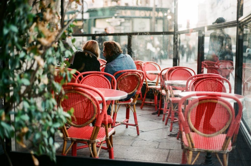 Romantic scene at a Parisian café featuring red chairs and a cozy ambiance.
