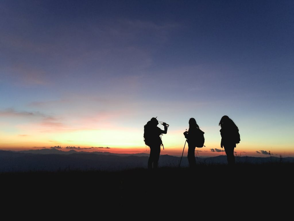 Group of hikers silhouetted against a vibrant sunset, enjoying an adventurous outdoor trek.